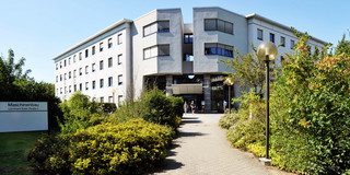 Maschinenbau-Gebäude Maschinenbau-Gebäude I: Ein großes weißes Gebäude mit zwei Flügeln. Davor ein Weg, der von Büschen gesäumt ist. Links im Bild ein Schild mit der Aufschrift "Maschinenbau, Leonhard-Euler-Straße 5".